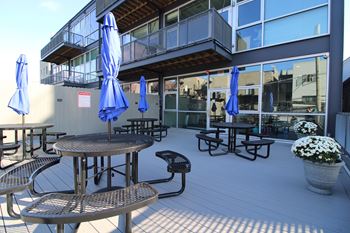 A patio with tables and chairs and umbrellas.